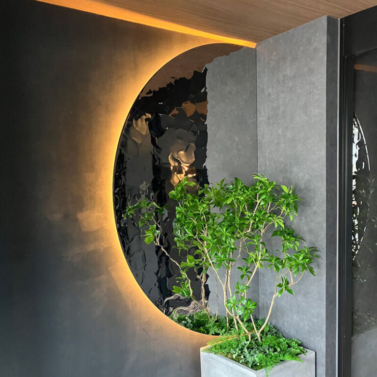 ジャンヴィエ・ルナ様のエントランス。円弧状のRipplesカットパネルの背面から光が漏れ、手前に植栽がある
